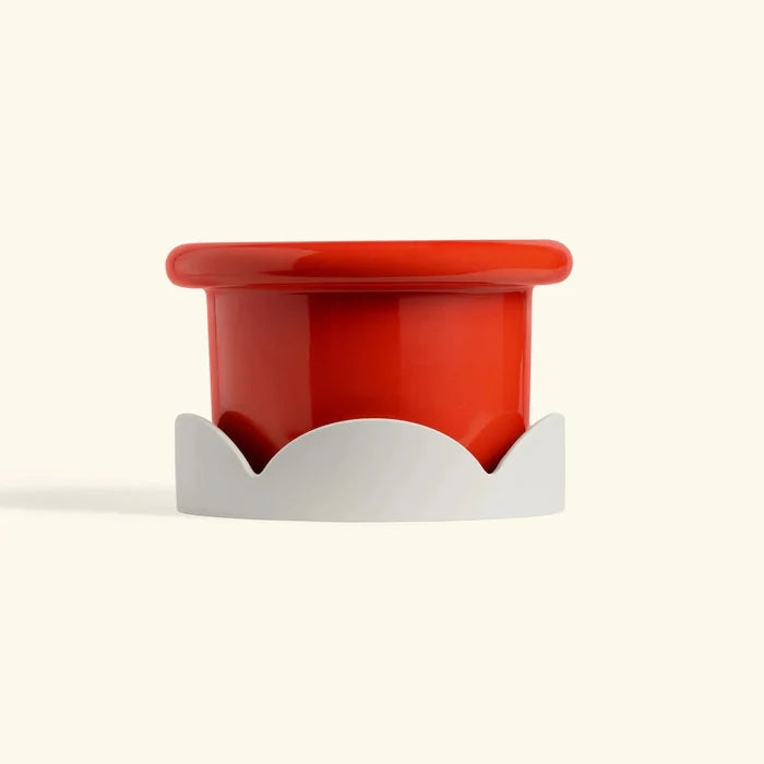 Red ceramic petal drip tray with beige base for home decor or plant protection on cream background