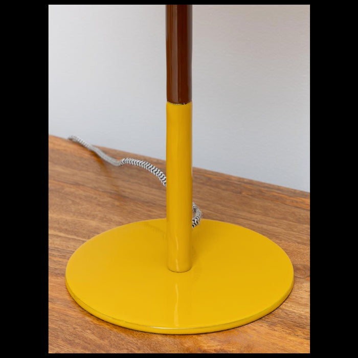 Close-up of a brown and yellow table lamp base sitting on a wooden surface with a braided cord visible