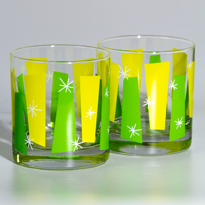 Two clear rocks glasses decorated with yellow and green geometric shapes and white star accents
