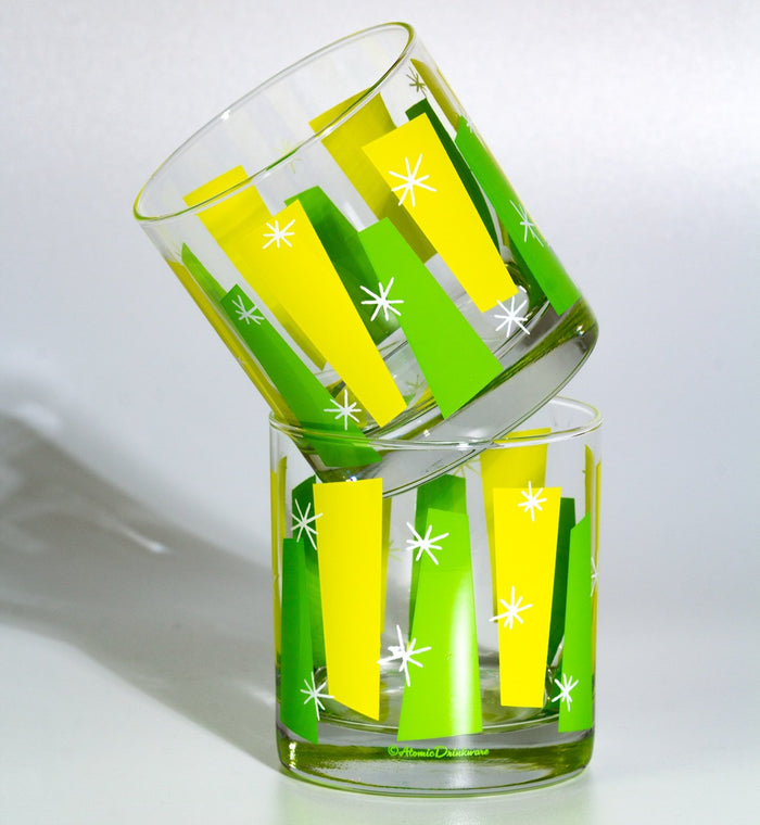 Two clear rocks glasses decorated with retro yellow and green geometric shapes and white starbursts