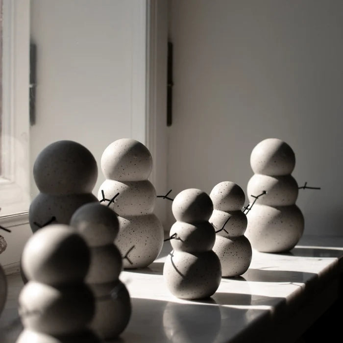 Minimalist ceramic snowmen with mole dot texture arranged on a windowsill in soft natural light