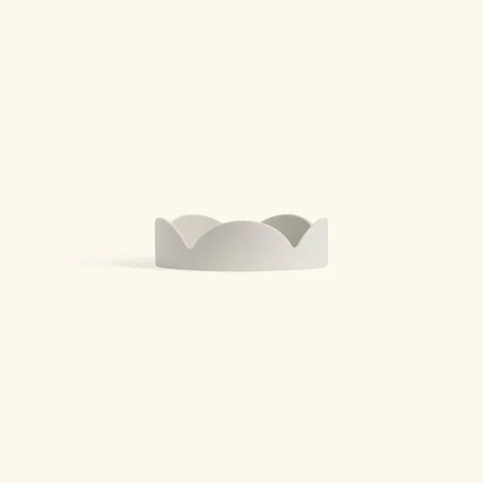 Minimalist oatmeal-colored ceramic drip tray with soft petal-shaped edges for home decor or planter use.