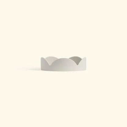 Minimalist oatmeal-colored ceramic drip tray with soft petal-shaped edges for home decor or planter use.