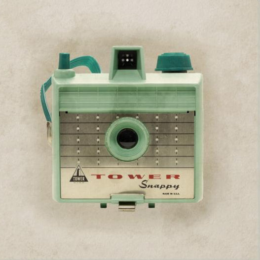 Close-up of a retro mint green vintage camera with geometric patterns and a textured background artwork.