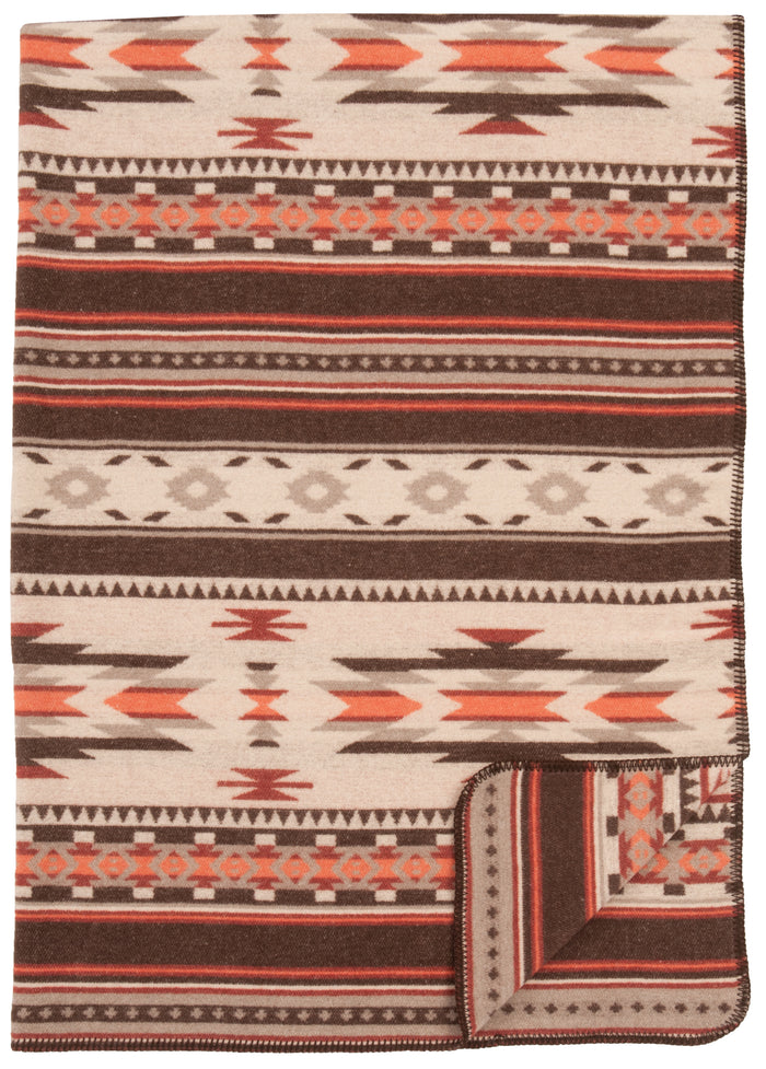 Soft wool blanket with geometric tribal patterns in brown, beige, and rust tones, folded at the corner.