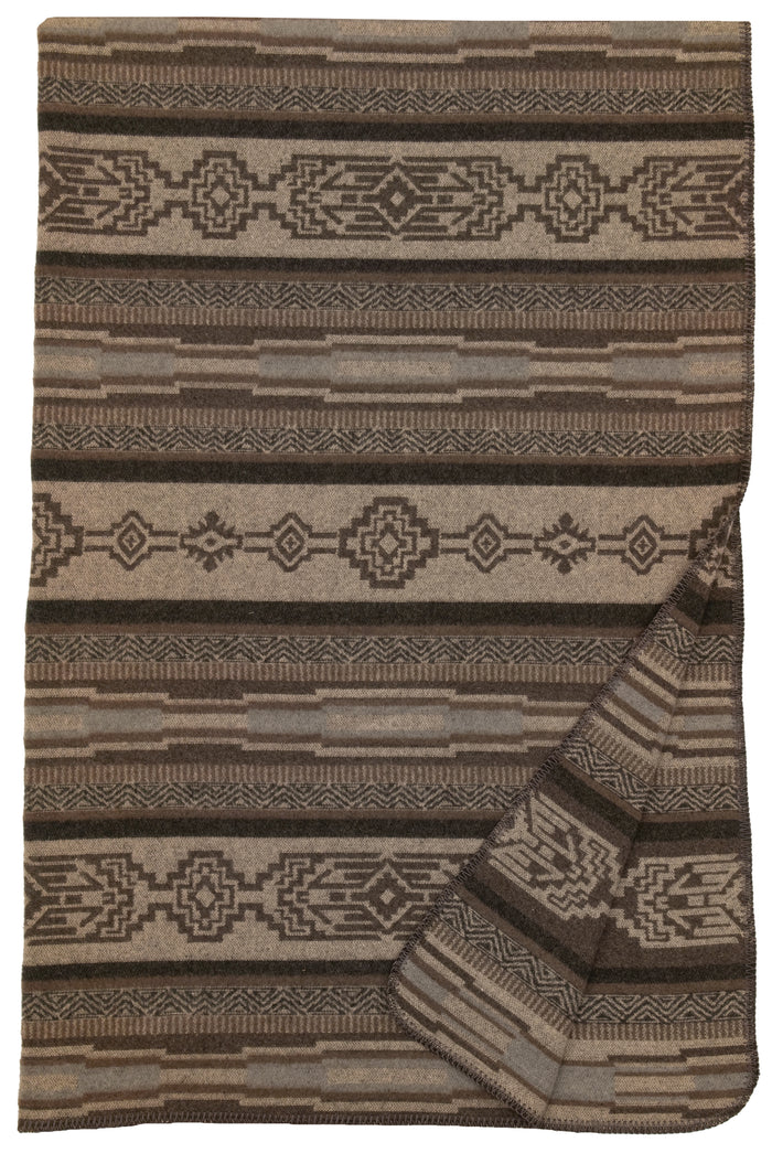 Brown and beige wool blanket with geometric tribal patterns and folded corner showing texture and thickness
