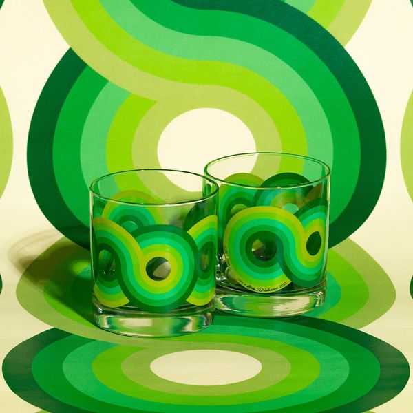 Two clear rocks glasses with overlapping green circular patterns on matching green abstract decor background
